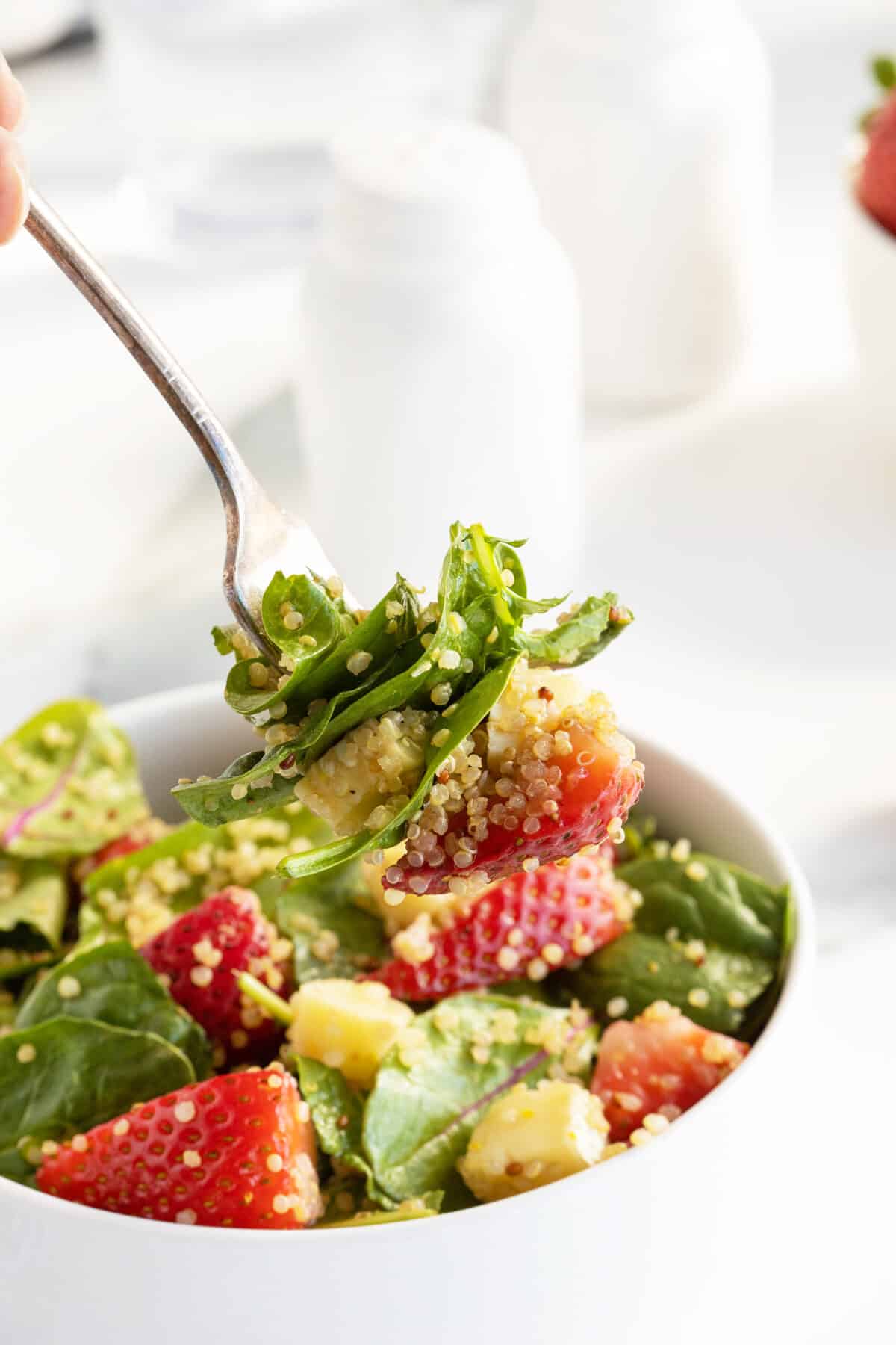 strawberry quinoa salad on a fork above a bowl