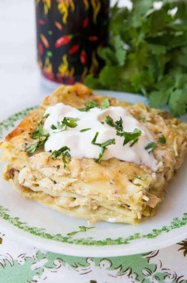 Close up Cheesy Green Chile Chicken Lasagna topped with sour cream and cilantro