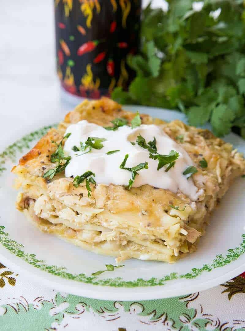 Close up Cheesy Green Chile Chicken Lasagna topped with sour cream and cilantro