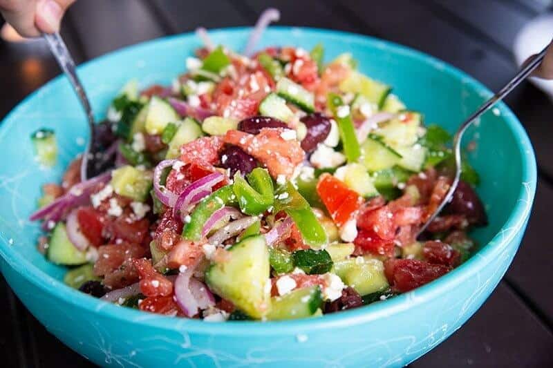 mixing the Greek Salad with Homemade Greek Salad Dressing using two spoons