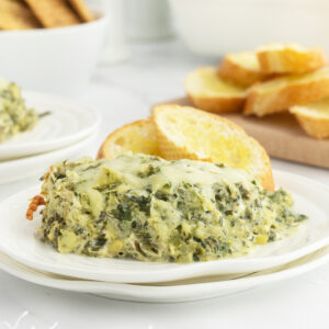 Hot and cheesy spinach and artichoke dip on a white plate