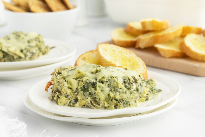 Hot and cheesy spinach and artichoke dip on a white plate