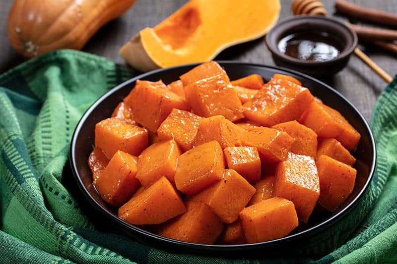 green tablecloth underneath black serving plate with Honey & Cinnamon Roasted Butternut Squash