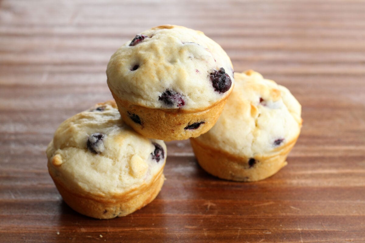 Stack of three saskatoon muffins on a wood table