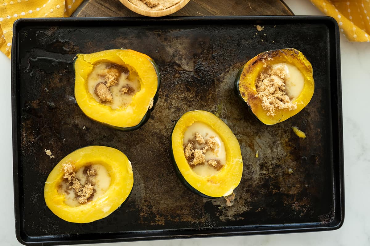 Acorn Squash with butter and brown sugar on center placed in a baking sheet