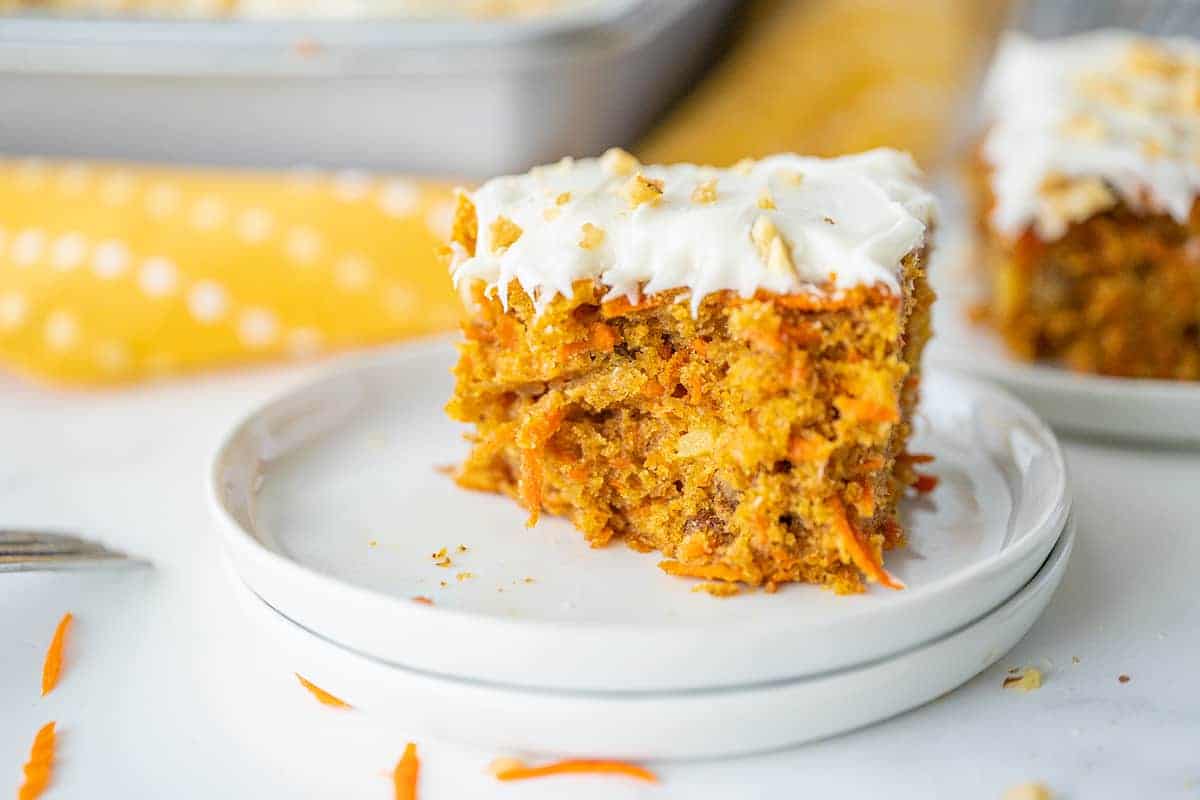 A slice of carrot cake on a plate with cream cheese icing