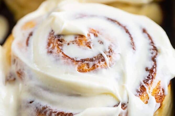 close up of a cinnamon bun with cream cheese icing slathered on top