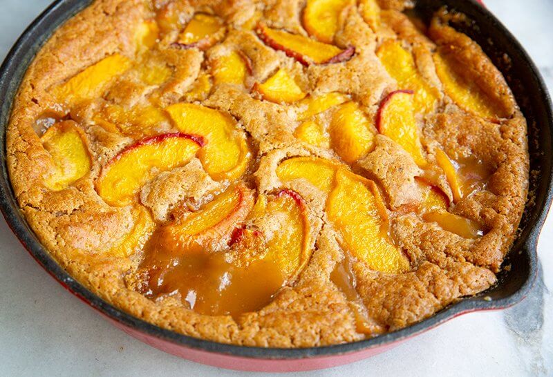 Bisquick™ Peach Cobbler in a large red iron skillet