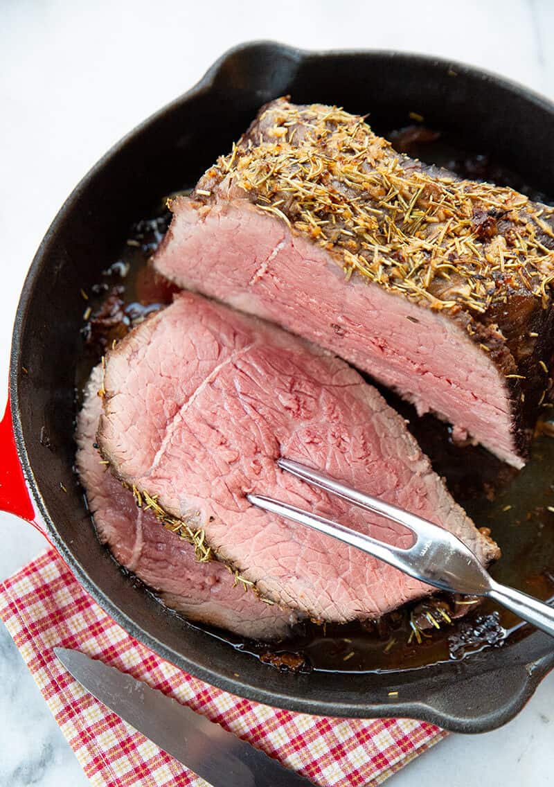 red checkered tablecloth underneath a red skillet with Herb & Garlic Bottom Round Roast