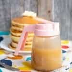 close up of Brown Sugar Sauce in a small pitcher like container, stack of pancakes in white plate on the background