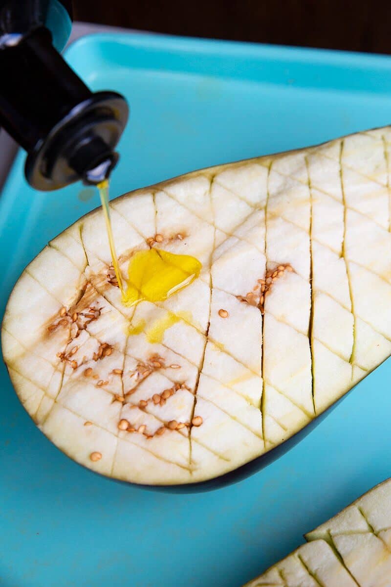 drizzling olive oil all over the top of eggplant sliced with a diamond pattern
