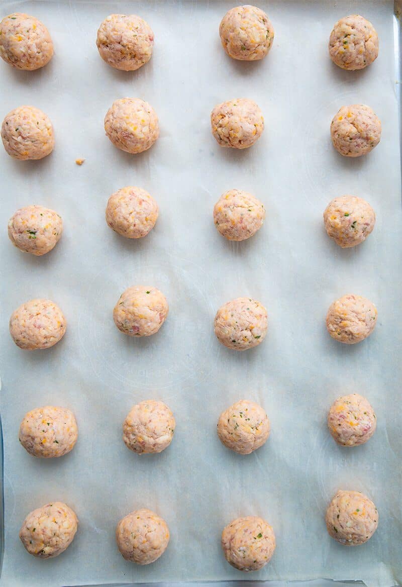 24 uncooked sausage balls on a baking sheet