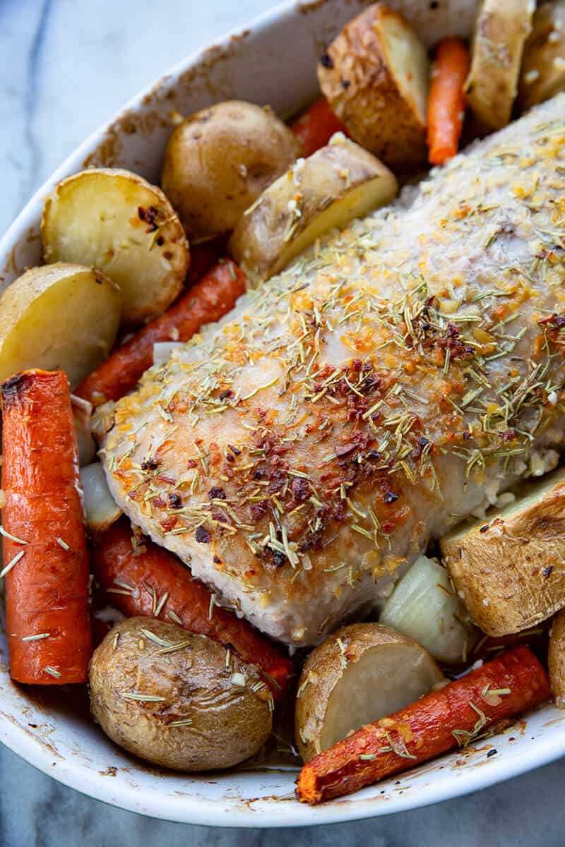 close up seasoned boneless Pork Loin Roast in a pan with potatoes and carrots