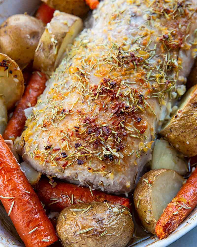 close up seasoned boneless Pork Loin Roast in a pan with potatoes and carrots