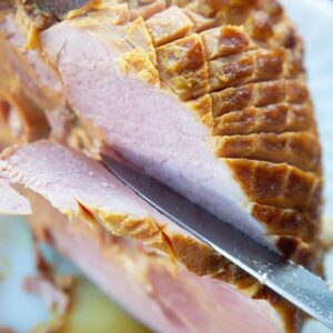 slicing a glazed precooked ham using a knife and fork