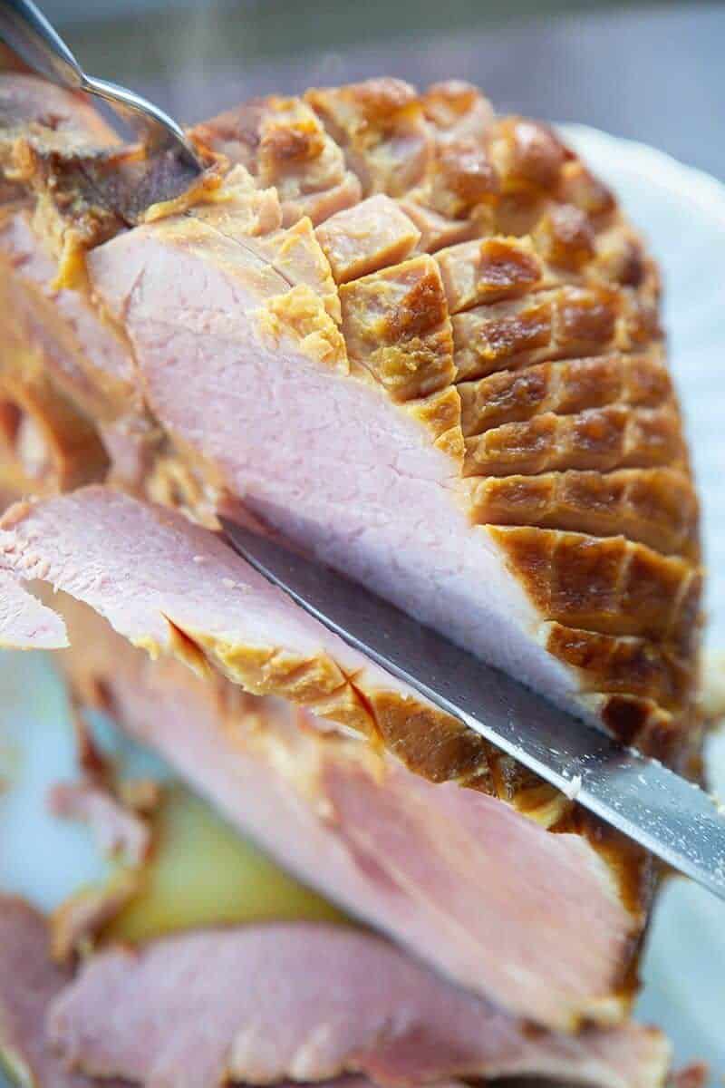slicing a glazed precooked ham using a knife and fork