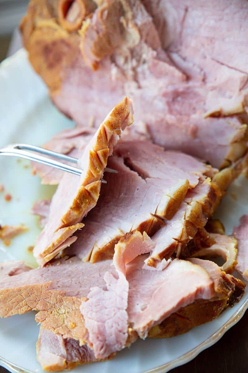 a slice of glazed precooked ham in a meat fork