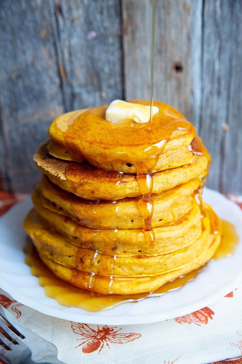 adding syrup on a stack of pumpkin pancakes