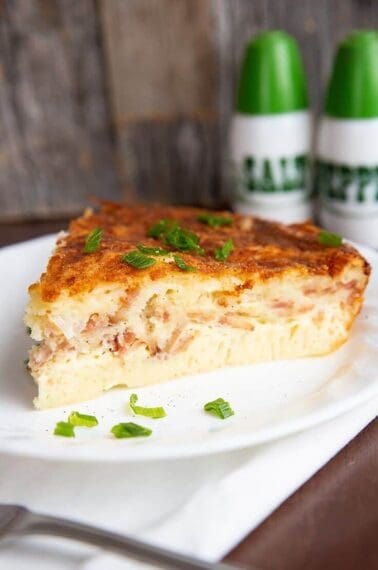 close up slice of Bisquick Quiche in a white plate, salt and pepper shakers on background