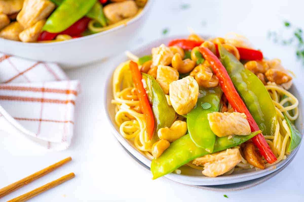 Cashew Chicken Stir Fry in a White Plate with Noodles