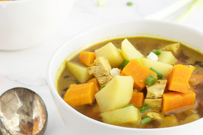 curried sweet potato and chicken soup with spoons beside bowl