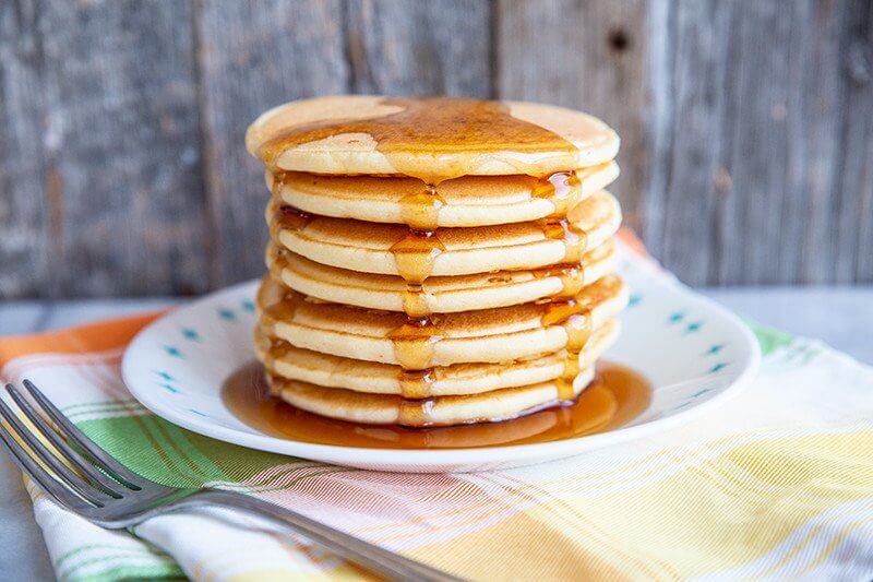 fork beside a plate with a stack of Bisquick® Pancakes topped with syrup