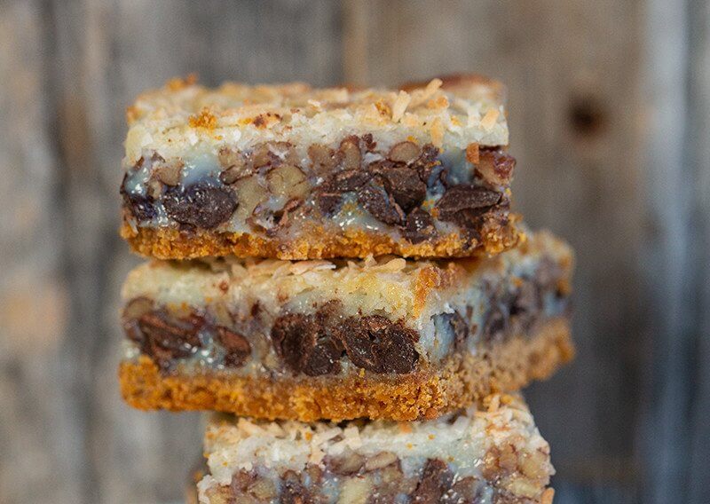 stack of Magic Cookie Bars / Hello Dolly Bars in wood background