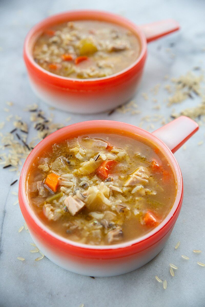 close up soup bowls of Turkey Carcass Soup in a marble table with some wild rice mix