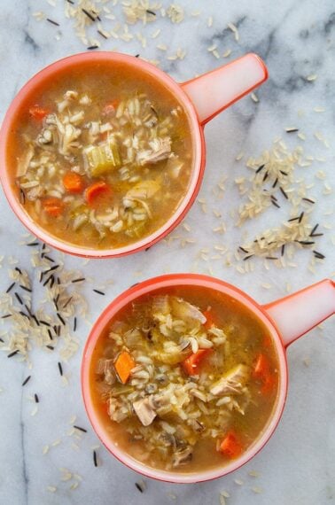 top down shot of Turkey Carcass Soup in a marble table with some wild rice mix