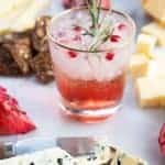 a glass of Pomegranate Gin Fizz garnish with rosemary sprig