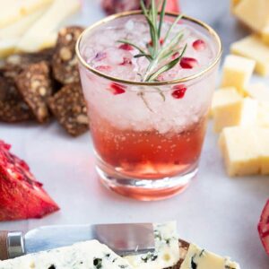 a glass of Pomegranate Gin Fizz garnish with rosemary sprig