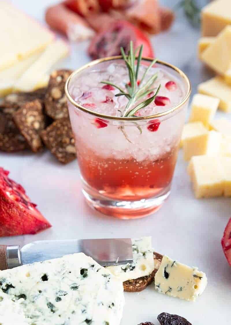 a glass of Pomegranate Gin Fizz garnish with rosemary sprig