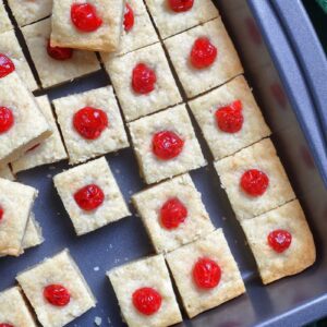 close up Shortbread Bites with candied cherries on top in a large baking sheet