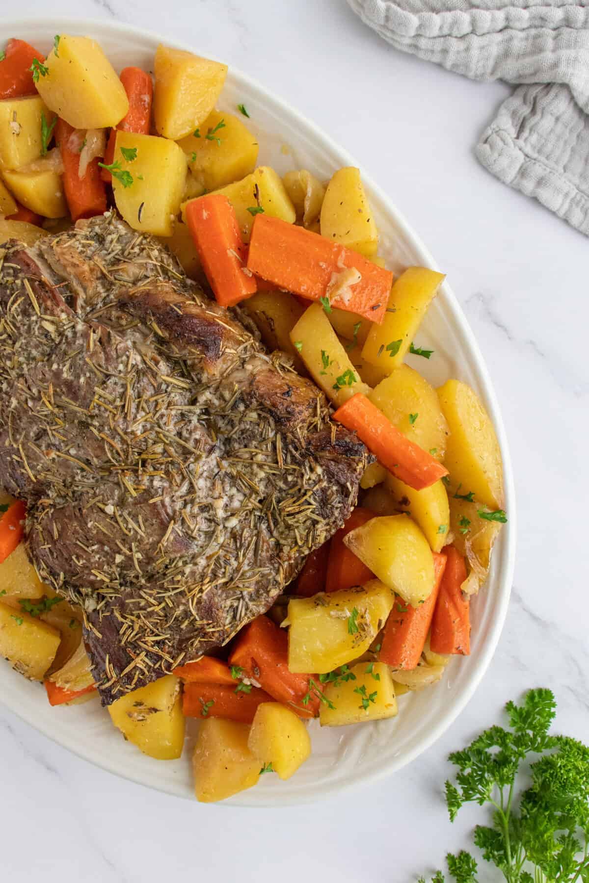 sirloin roast on a white platter surrounded by vegetables