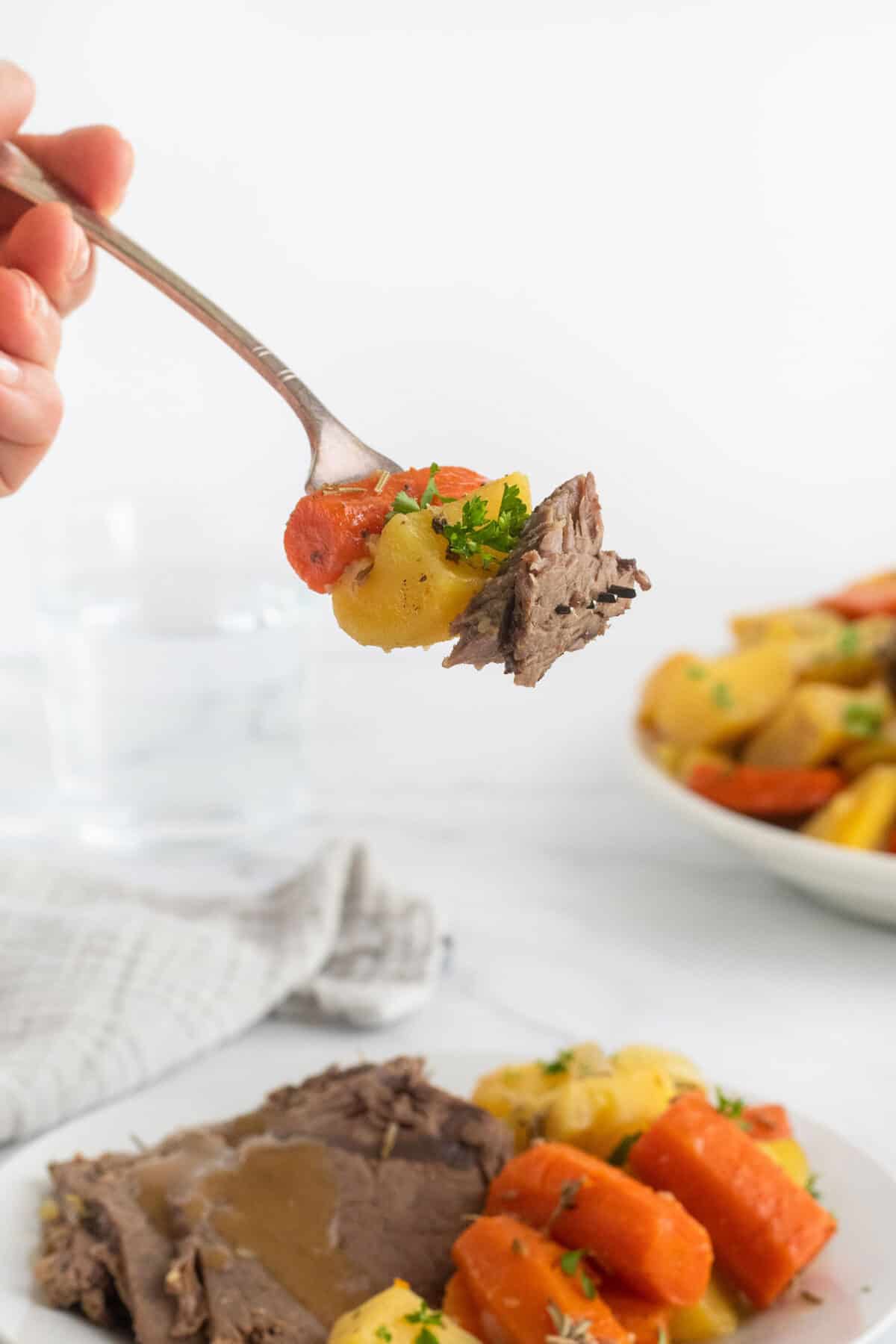 fork with potato, carrot and sirloin roast on it 