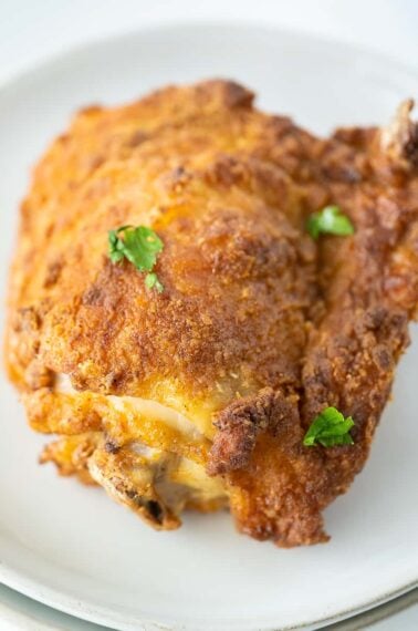 close up of crispy-skinned air fryer chicken on a white plate