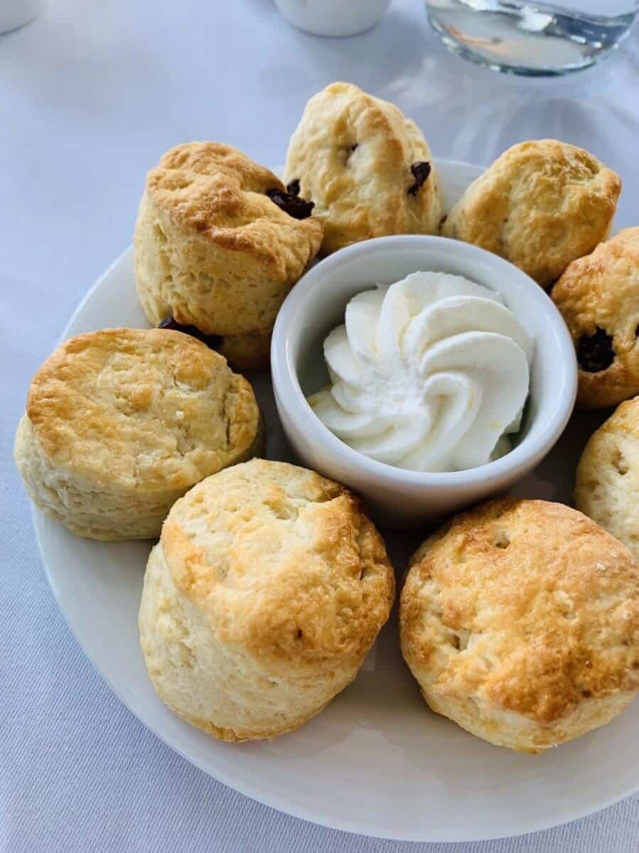 scones on a small plate and a round white small container of condiments