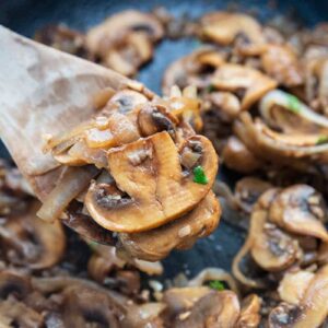 wooden cooking spoon with some Sauteed Mushrooms and Onions