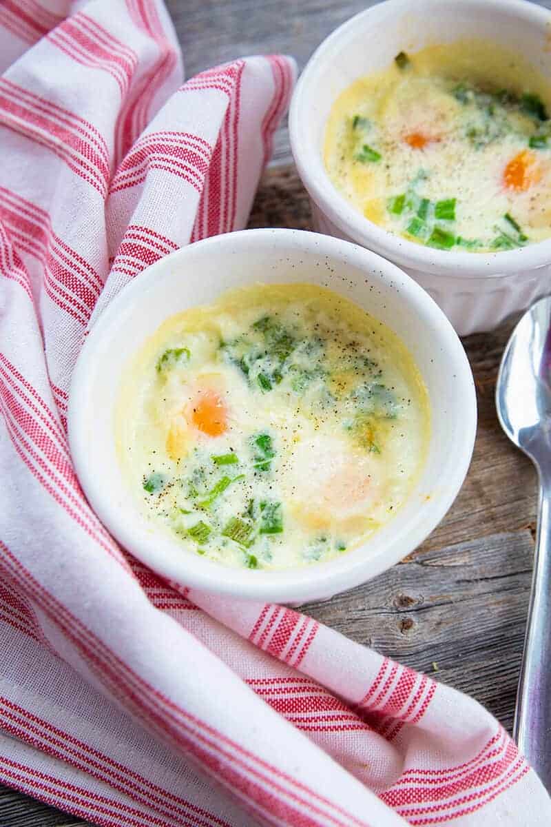 close up Shirred Eggs in a white soup bowl saucers