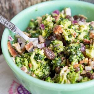 close up Bacon Broccoli Salad Recipe in a green Jadeite bowl with a spoon