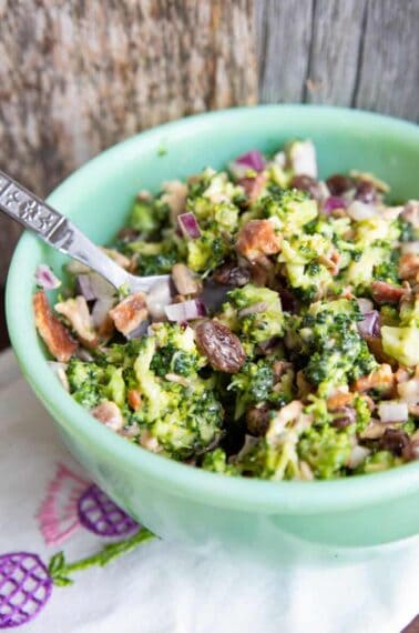 close up Bacon Broccoli Salad Recipe in a green Jadeite bowl with a spoon