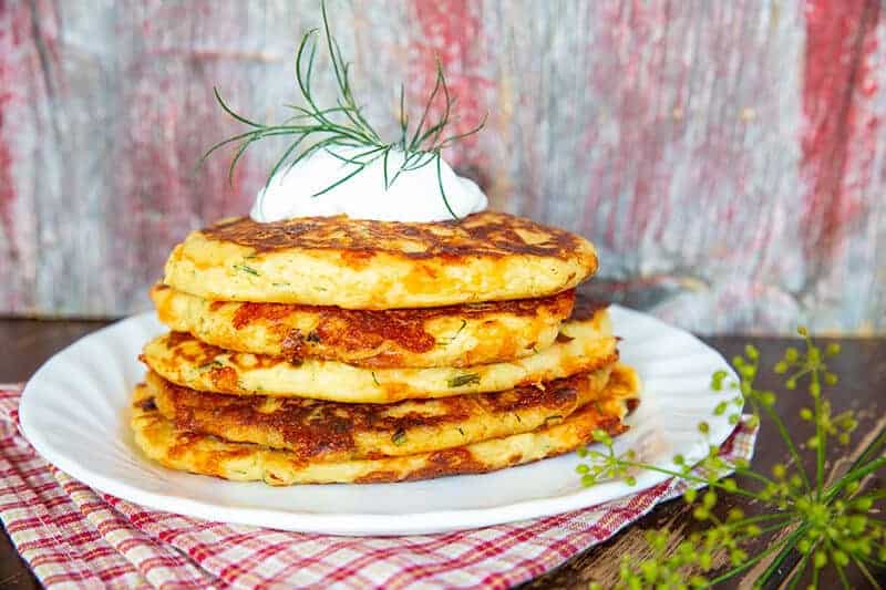 stack of Cheesy Dill & Garlic Mashed Potato Cakes with a dollop of sour cream on top