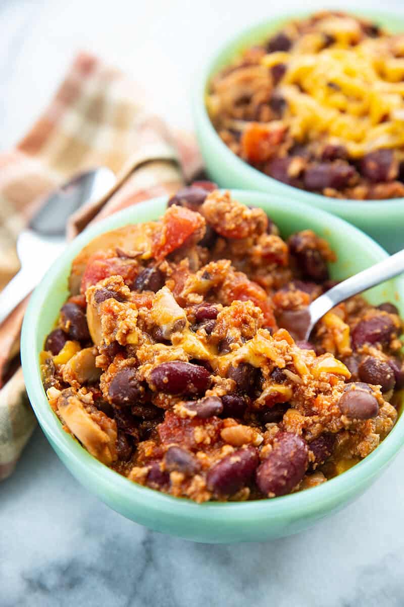 bowl of Ground Turkey Chili with grated cheese on top and a spoon in it