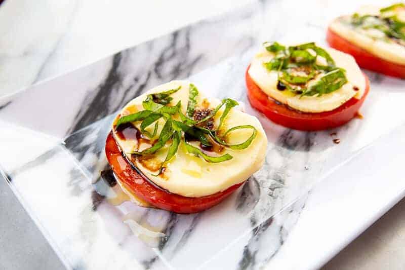 3 pieces Traditional Caprese Salad in a marble designed serving plate