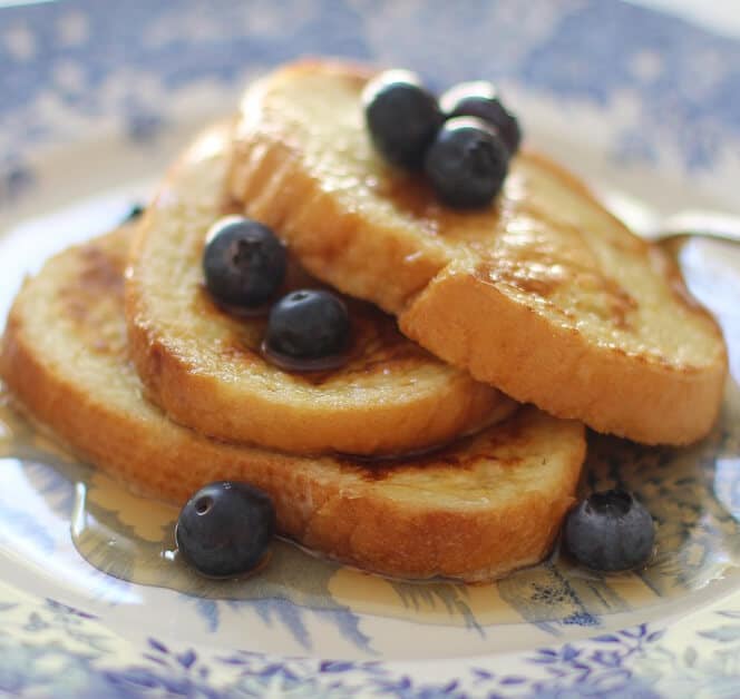 french toast topped with syrup and blueberries. 