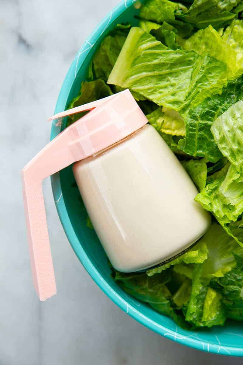 close up Homemade Creamy Caesar Salad Dressing in a pink container