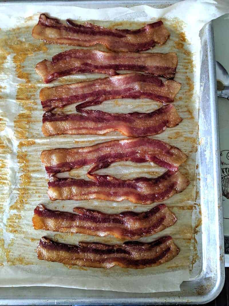 crispy oven baked bacon on a baking sheet with parchment paper