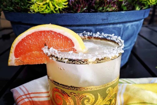 checkered tablecloth underneath a glass of Paloma Cocktail with Salted Rim garnish with a slice of grapefruit
