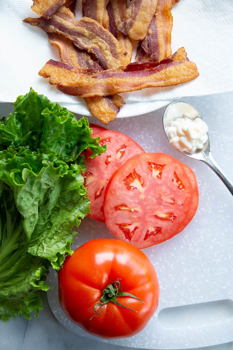 cooked bacon, sliced tomatoes, lettuce and mayonnaise in spoon