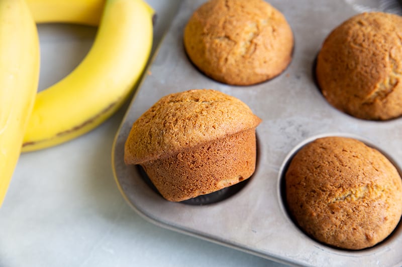 Banana Bread Muffins in muffin tins, rife bananas on background
